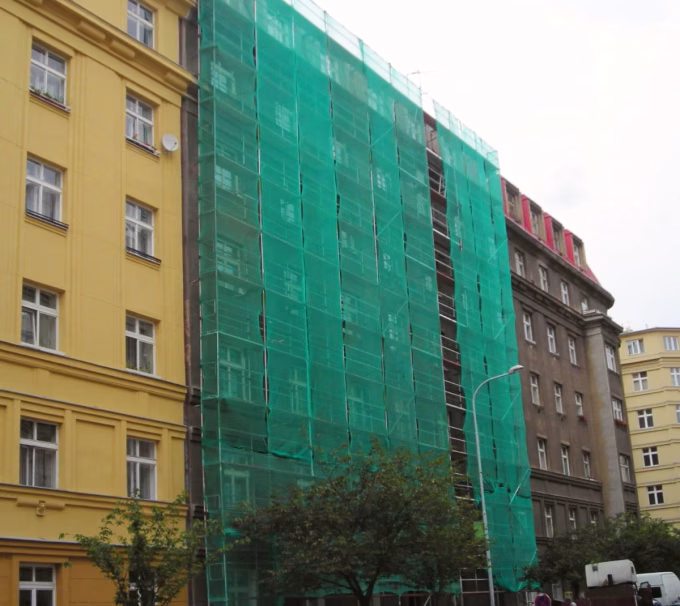Lešení se sítí na fasádě činžovního domu