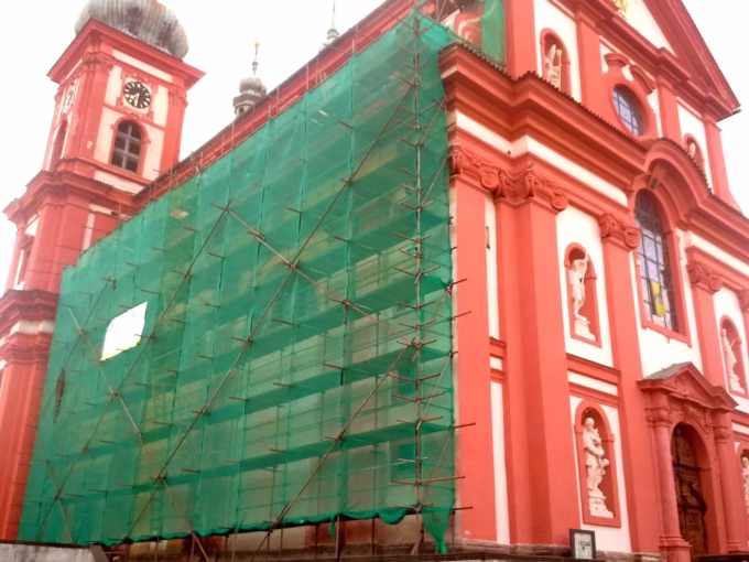 Lešení se sítí na fasádě barokního kostela
